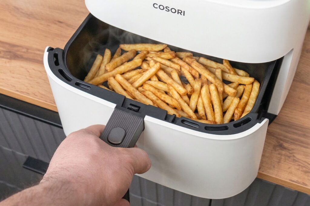 The basket pulls out from the front. Just press the button and pull toward you.