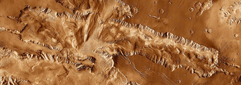 Candor Canyon on a mosaic of THEMIS infrared images, with fragments of Ophir, Melas, and Juventae canyons at the top, lower left corner, and far upper right corner respectively. Image source: en.wikipedia.org. Photo.