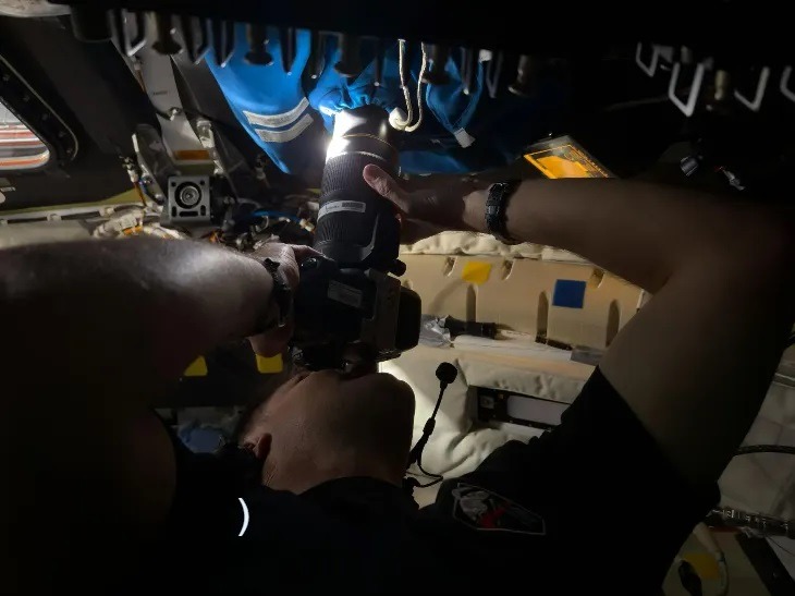 Astronaut Jeremy Hansen takes a photo through the camera shroud/curtain covering window No. 2 of the Orion spacecraft.