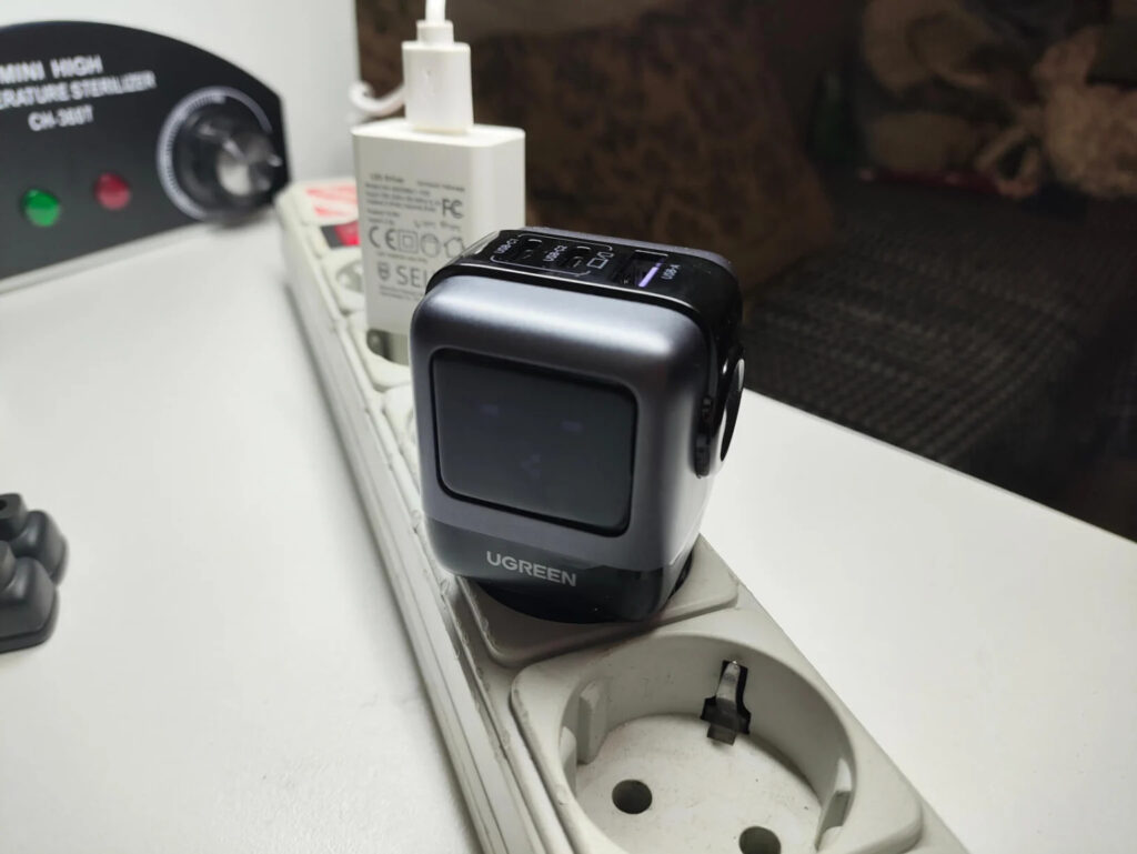 Fast charger for iPhone, iPad, and Mac in a stylish design. The charger has its own small screen. Photo.