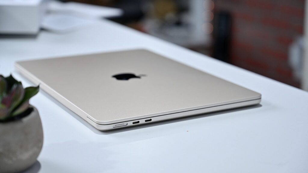 An open MacBook being carried by hand