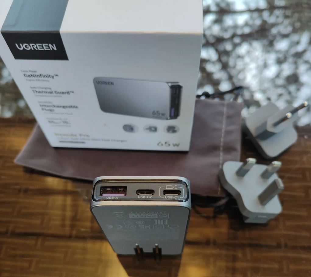 65W charger with adapters for different outlet types. The charger is very flat — it sits flush against the wall. Photo.