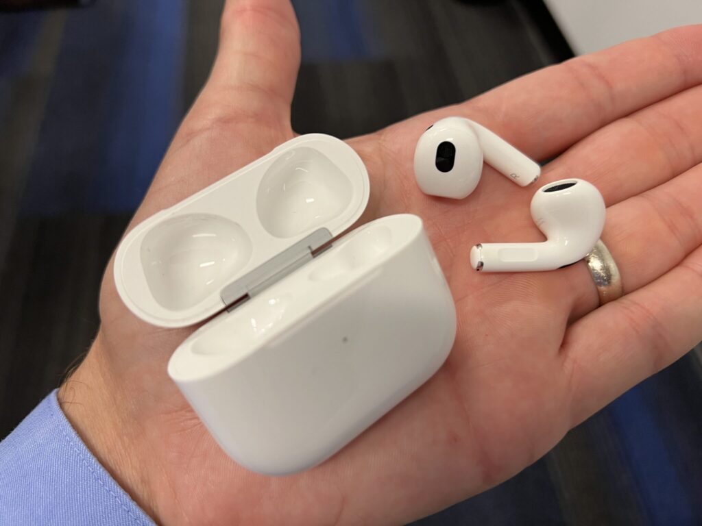 AirPods 5 resting on a hand alongside the case