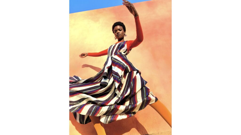 A model in a striped dress against an orange wall