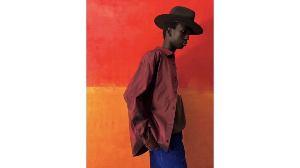 A man in a hat against a red-orange wall